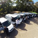 an image of a fleet of vans with their drivers